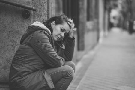 Un femme triste s'assoit toute seule dans la rue. Elle est atteinte d'une dépression.