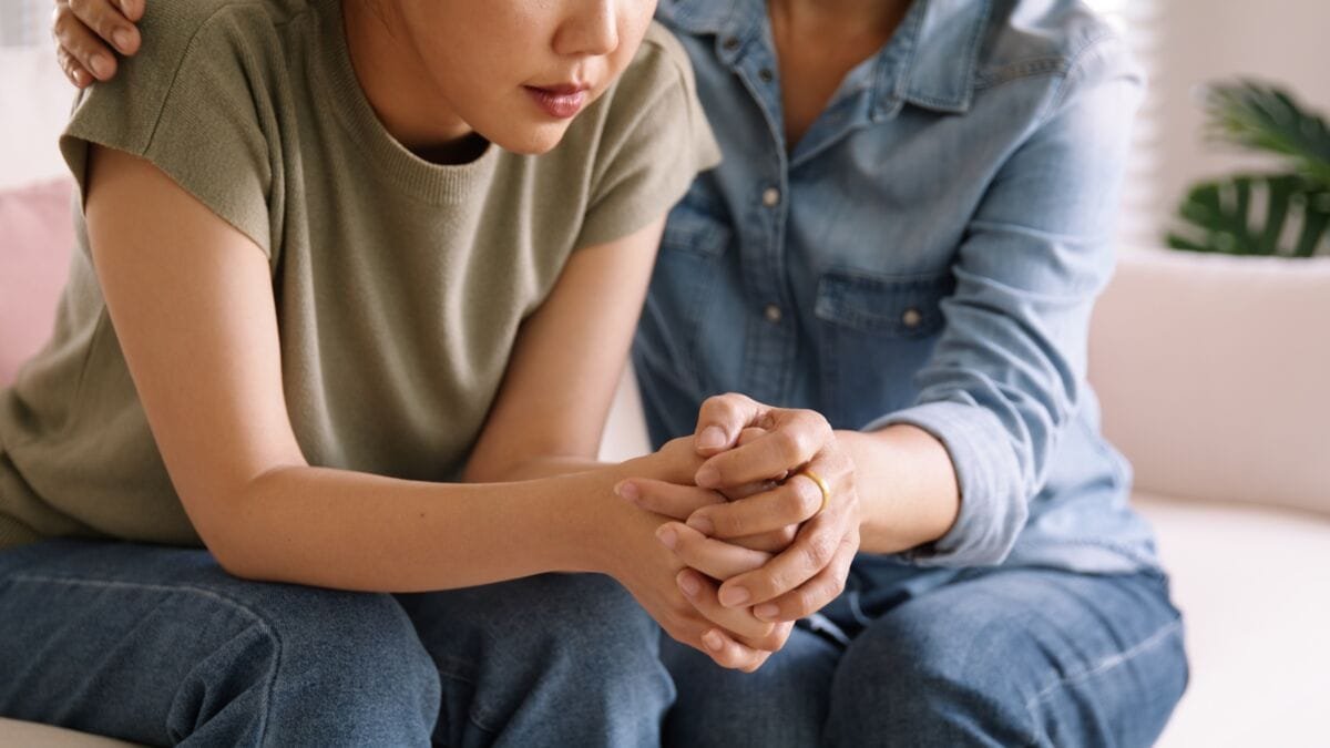 Une femme tient la main d'une autre pour l'aider à lutter contre sa dépression