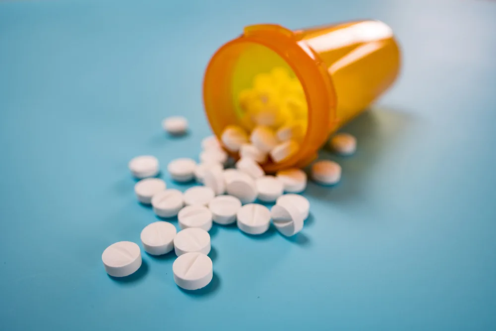Pile of white pills on blue background On peut traiter la dépression par la prise de médicaments