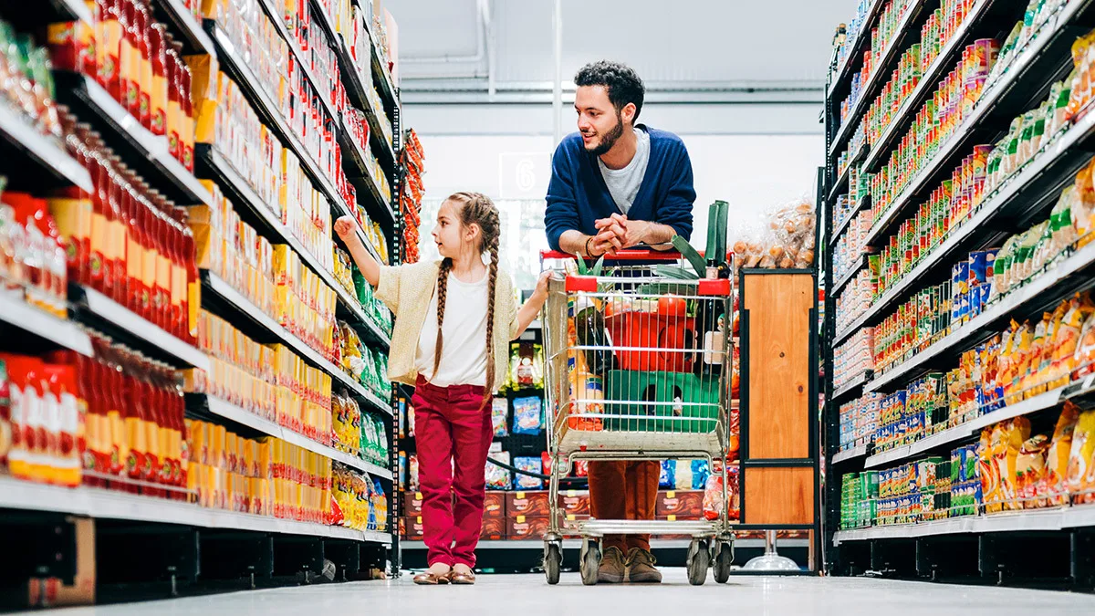 father and daughter with trolley in supermarket aisle Faire les courses sereinement sans l'oniomanie.