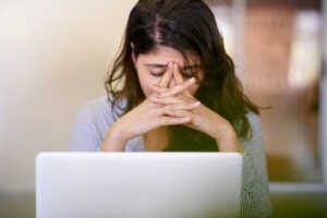 Une femme faisant un burn-out devant son ordinateur.