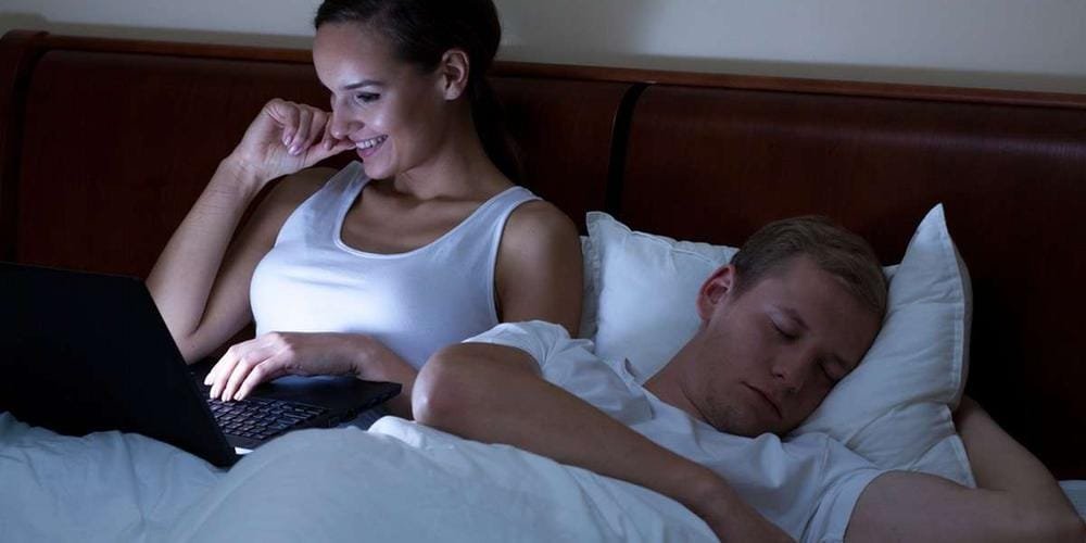 so-5d5feb8b66a4bdb6499b31ce-ph0 Une femme devant son ordi en pleine nuit, alors que son conjoint dors à côté.