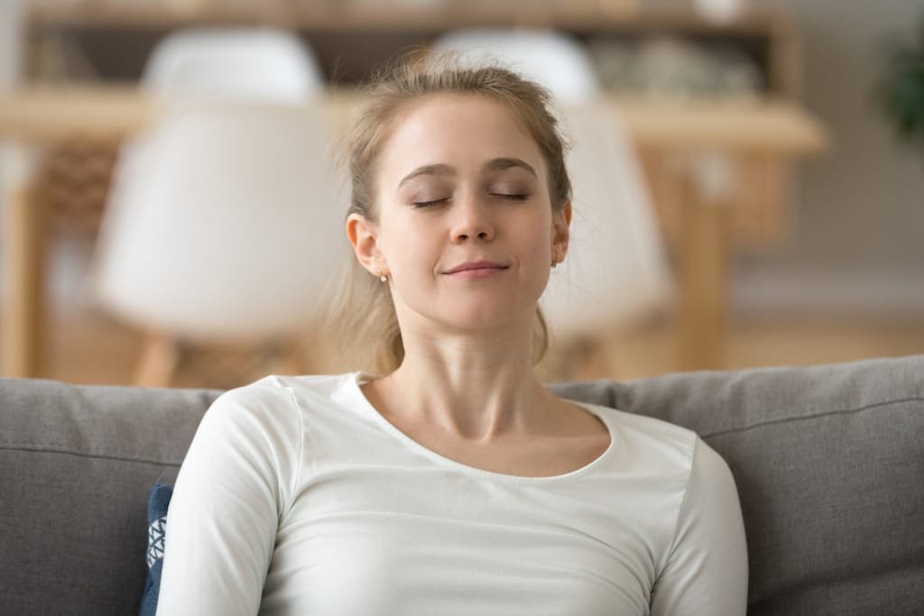 Close up calm peaceful woman relaxing with closed eyes on sofa 5 astuces pour combattre son angoisse