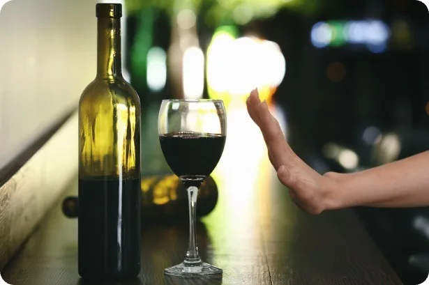 Main refusant un verre de vin sur un comptoir