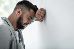 Un homme déprimé s'appuyant la tête contre un mur.