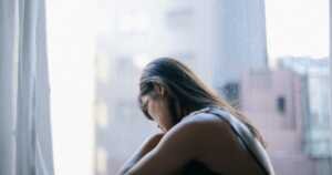 deprime-ou-depression Une femme déprimée, seule, assise devant une fenêtre.