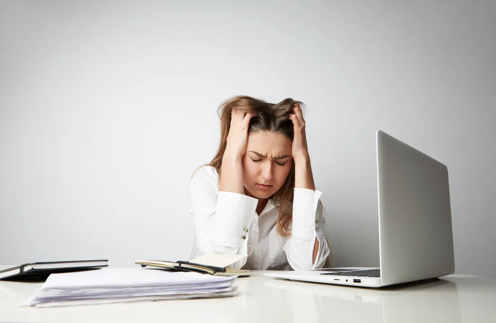 Tired,Beautiful,Young,Woman,In,A,White,Shirt,Working,On Une femme stressée et déprimée devant son ordinateur.