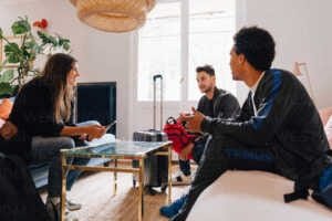 Full length of friends talking while sitting on sofa in living room Les proches sont de grand soutien dans la lutte contre l'addiction.