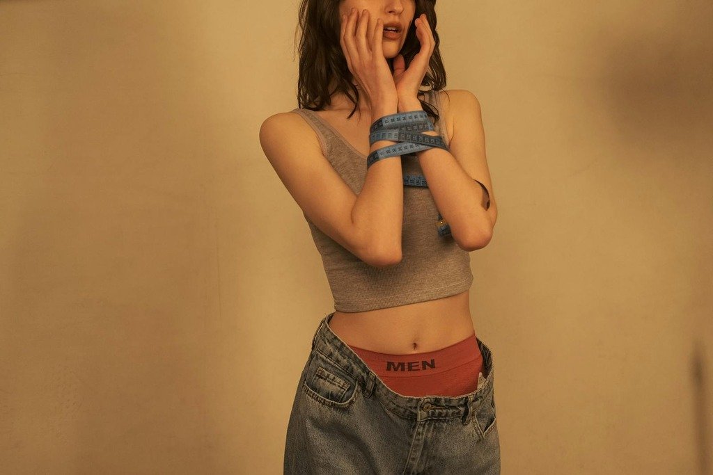 Young woman in casual attire with a tape measure wrapped around her hands.