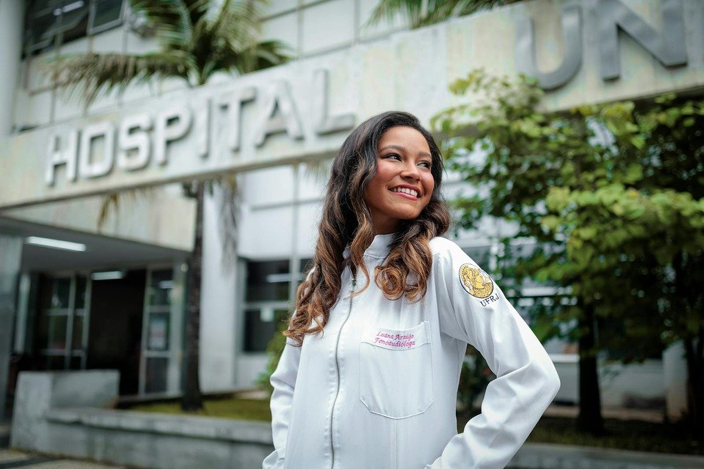 Smiling female doctor standing confidently outside a hospital building.