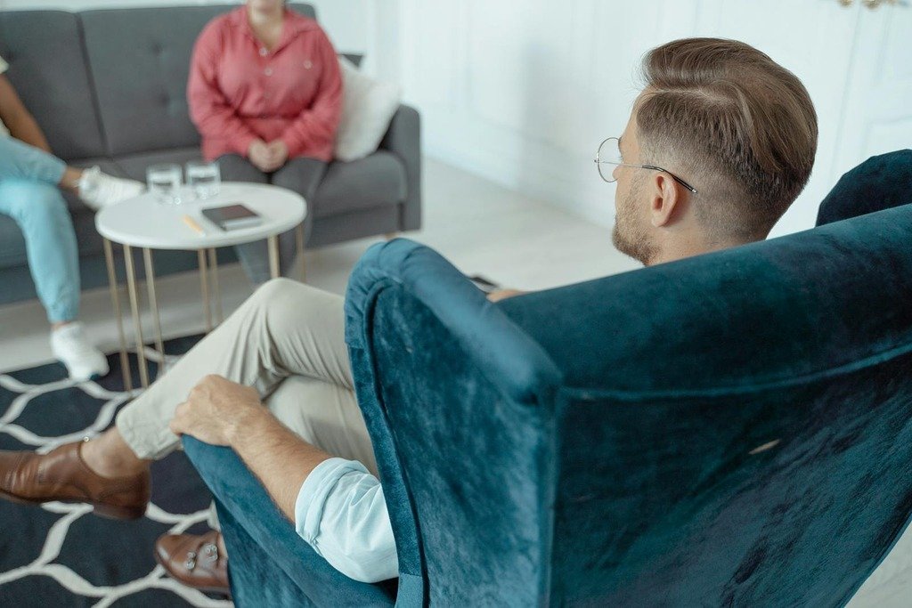 A man having a counseling session with a therapist in a modern office setting.