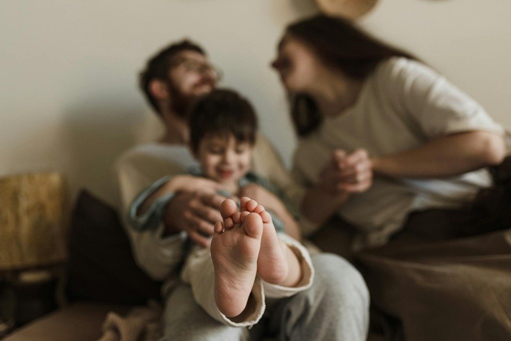 A family enjoying a cozy moment with focus on child's feet, symbolizing warmth and affection.