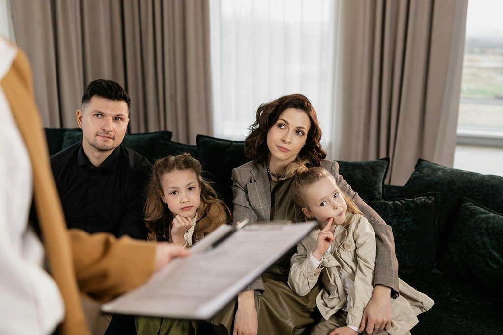 A family attentively listens during a consultation in a cozy living room setting.