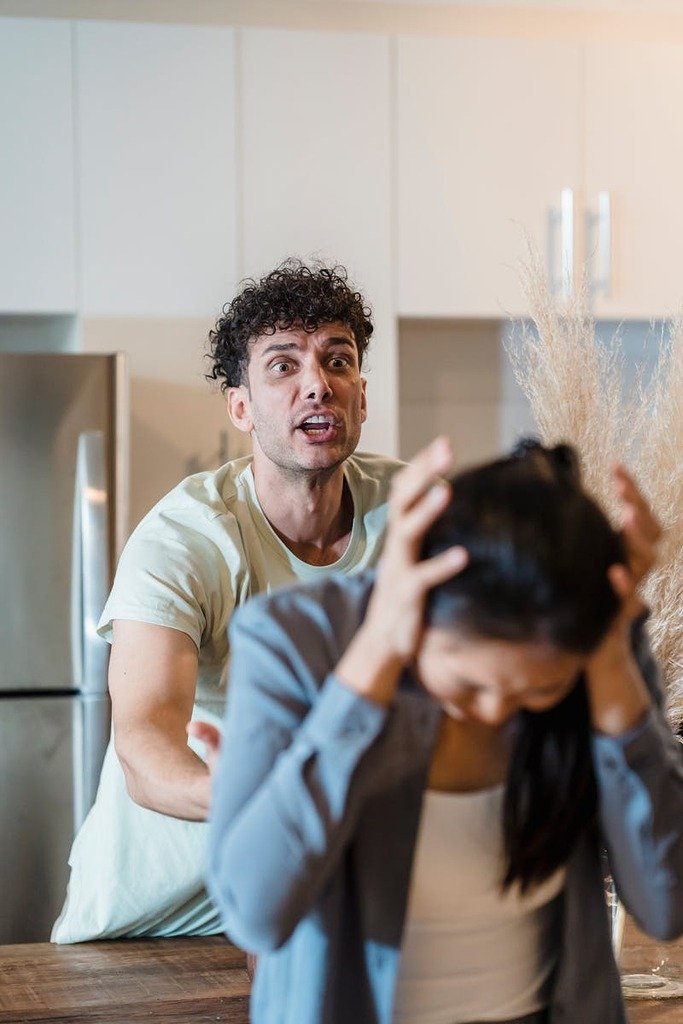 A man and woman in a tense emotional confrontation in a kitchen setting.